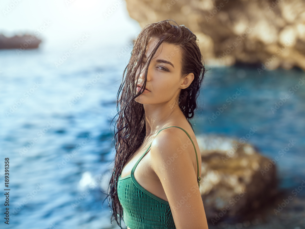 Portrait of beautiful young woman on wild rocky beach.