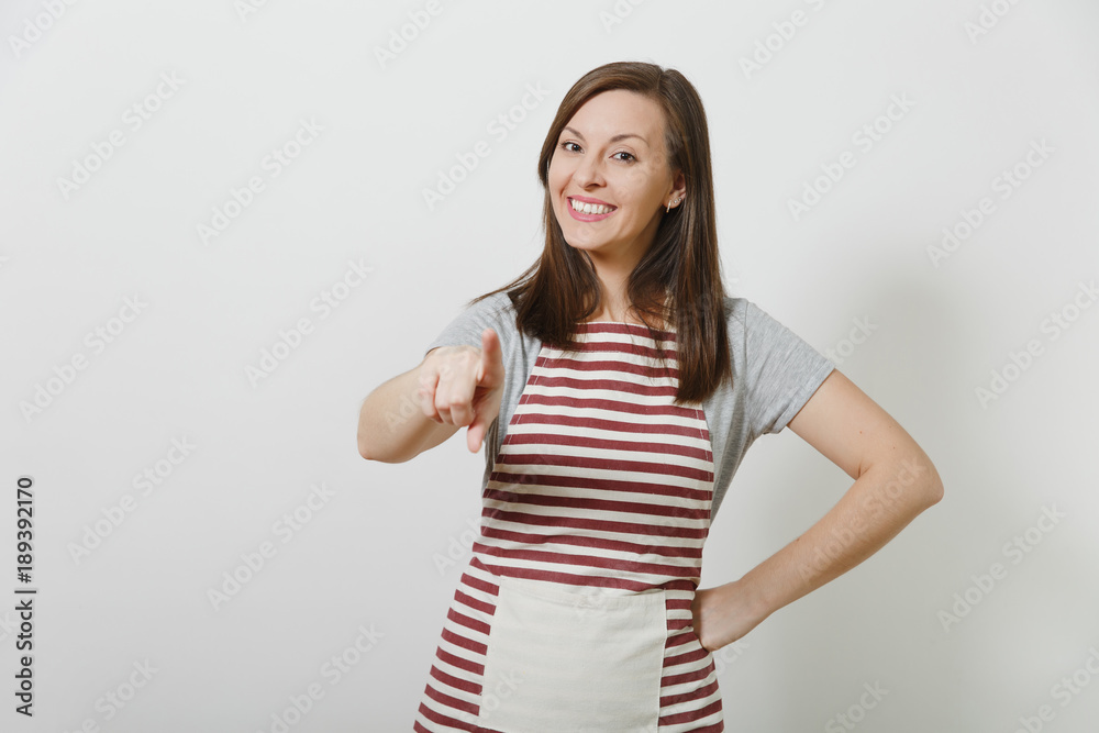 Young attractive smiling brunette caucasian housewife in striped apron isolated on white background. Beautiful housekeeper woman pointing index finger and looking camera. Copy space for advertisement. Young attractive smiling brunette caucasian housewife in striped apron isolated on white background. Beautiful housekeeper woman pointing index finger and looking camera. Copy space for advertisement.