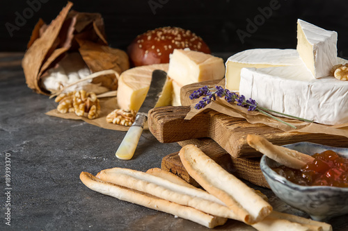 French national food. Cheese with mold. A delicious appetizer for wine. Doux et cremeux, munster cerome, Banon. Dark background.