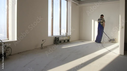 Man polishing marble floor in modern office building. Man works with grinding machine for floor photo