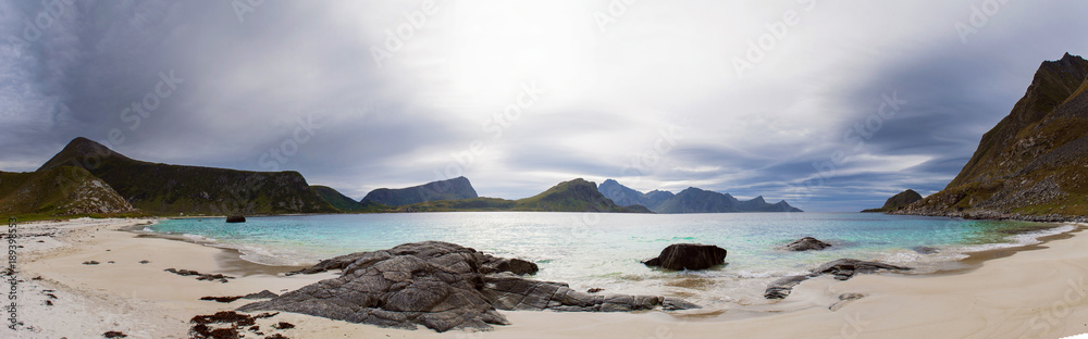 Panorama of Haukland beach on the Lofoten islands in cloudy weather. Mountains, sandy beach and azure water. Norway sea.
