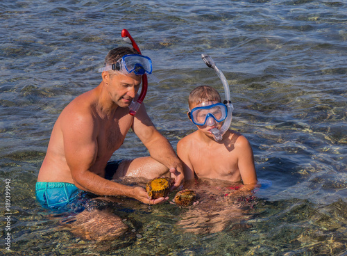 Father and sun diver find two big shells in the Aegean clear  sea. photo