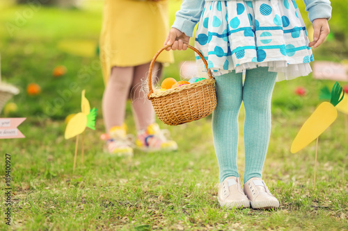 Little girl with basket of colorful eggs in park. Easter hunt concept