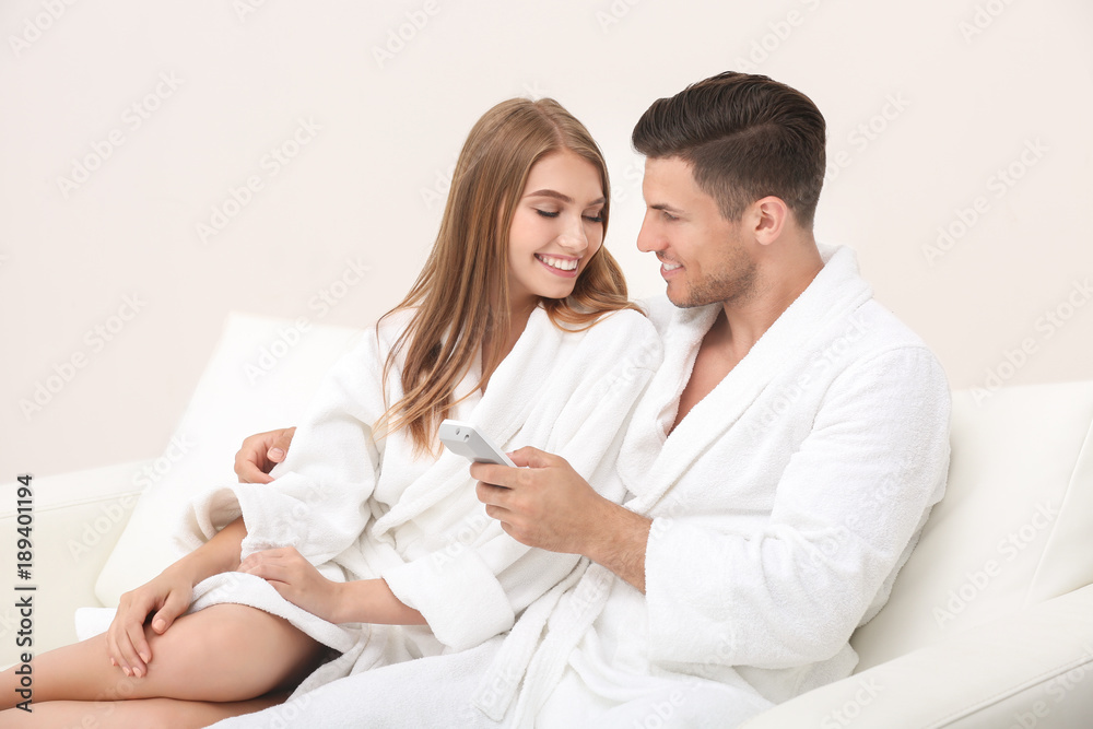 Young loving couple in bathrobes relaxing on sofa Young loving couple in bathrobes relaxing on sofa
