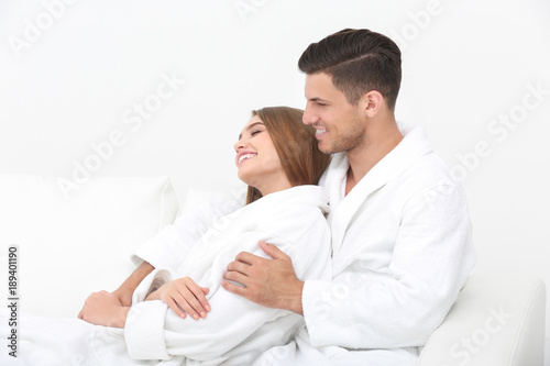 Young loving couple in bathrobes relaxing on sofa