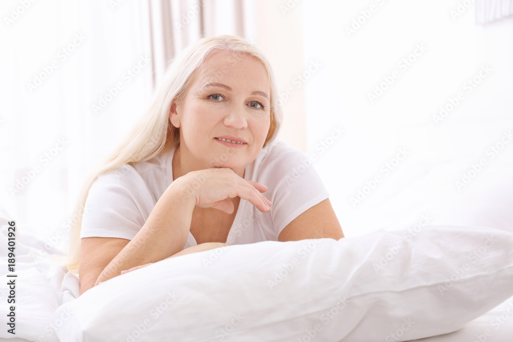 Senior woman lying on white pillow at home Senior woman lying on white pillow at home