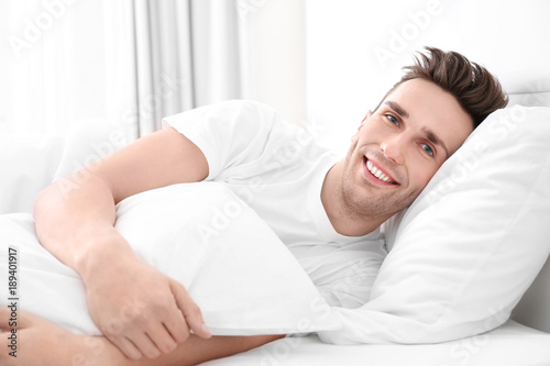 Young man lying on white pillow at home