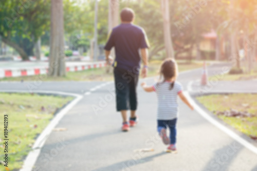 Blurred photo of Asian American little girl walking and playing with dad in green park outdoor © MIA Studio
