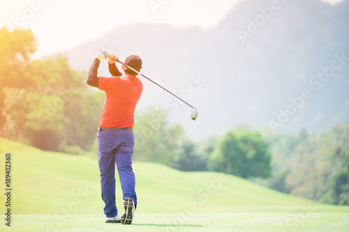 Golfer hitting golf shot with club on course while on summer vacation,Man playing golf on a golf course in the sun
