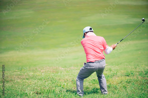 Golfer hitting golf shot with club on course while on summer vacation,Man playing golf on a golf course in the sun