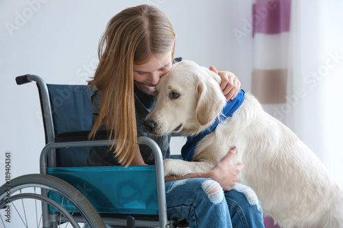 Girl in wheelchair with service dog indoors