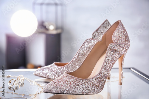 Beautiful high heeled shoes and jewelry on table