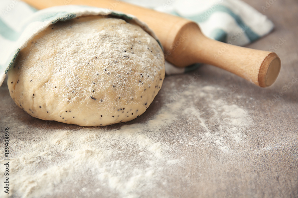 Raw dough with poppy seeds and rolling pin on table Raw dough with poppy seeds and rolling pin on table
