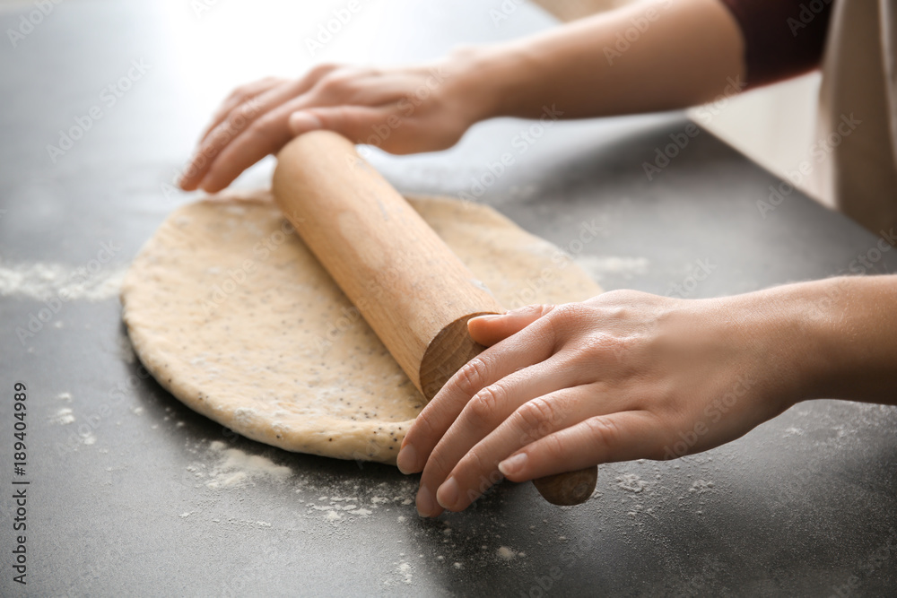 Woman rolling dough with poppy seeds on table, closeup Woman rolling dough with poppy seeds on table, closeup