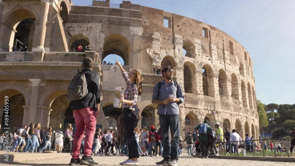 Three young friends tourists standing in front of colosseum in rome