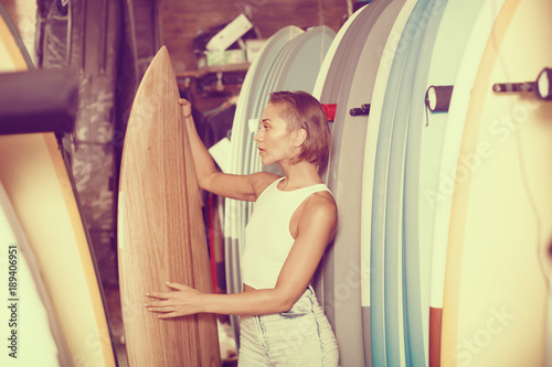 Positive female holding surfboard in the sports store © JackF