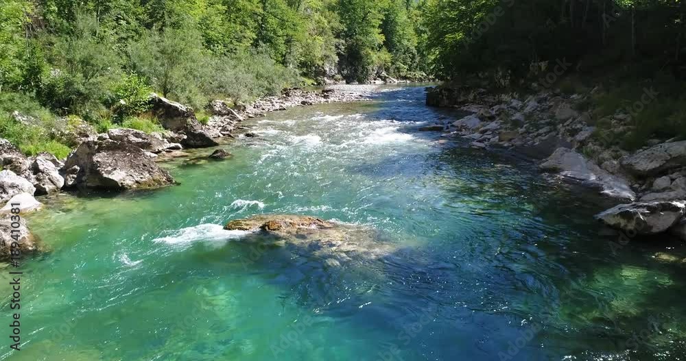 Flight over the river with clear water flowing along the stony bottom. Montenegro.