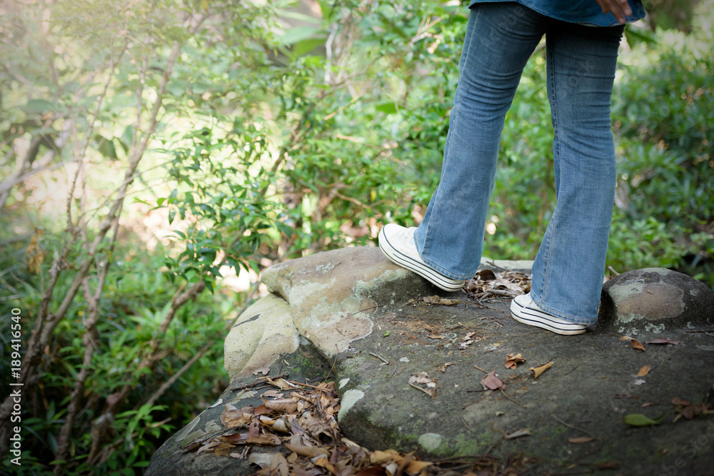 Beautiful Asian girl wearing a hat and backpack riding in the jungle on the mountain. Holidays and Nature Concept. Beautiful Asian girl wearing a hat and backpack riding in the jungle on the mountain. Holidays and Nature Concept.