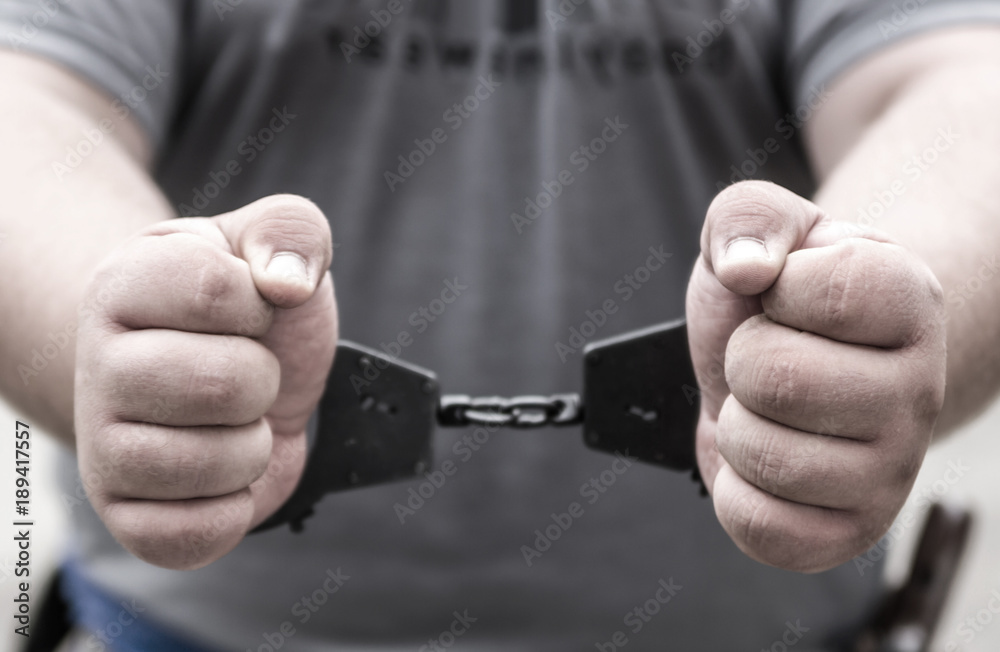 Hand criminal in handcuffs the focus on his fists close up. Arrest detention criminal