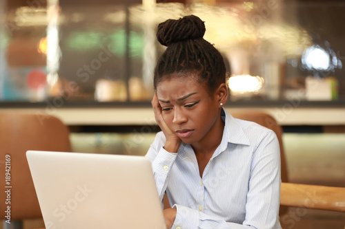 Young student with laptop looking confused
