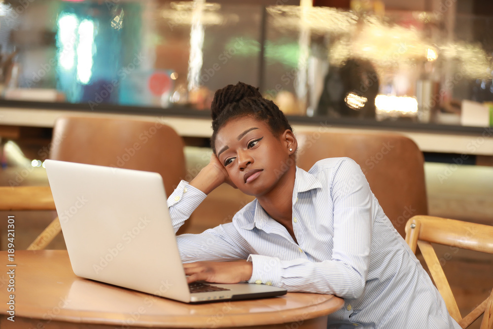 Tired young girl looking at laptop