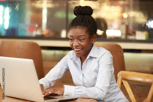 Excited young black woman watching laptop