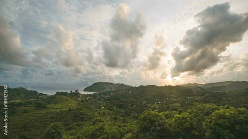 Sunset and moving clouds over the bay and valley in Kuta beach, Lombok Indonesia photo