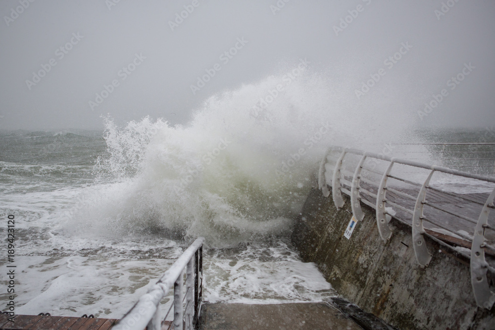 storm on shore in winter. strong storm in blizzard. Waves break sea embankment in winter storm.