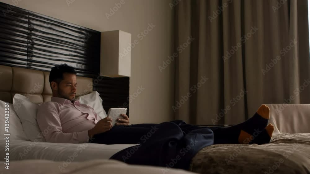 Businessman using digital tablet in bedroom Businessman using digital tablet in bedroom