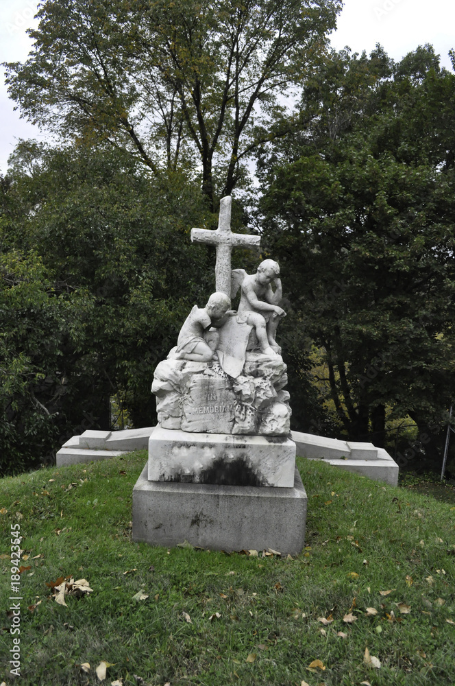 Statue of Two Angel Children with a Cross in a Cemetery