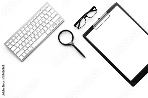 Monochrome white and black work desk with pad, glasses, keyboard, magnifiger on white background top view copy space mock up photo