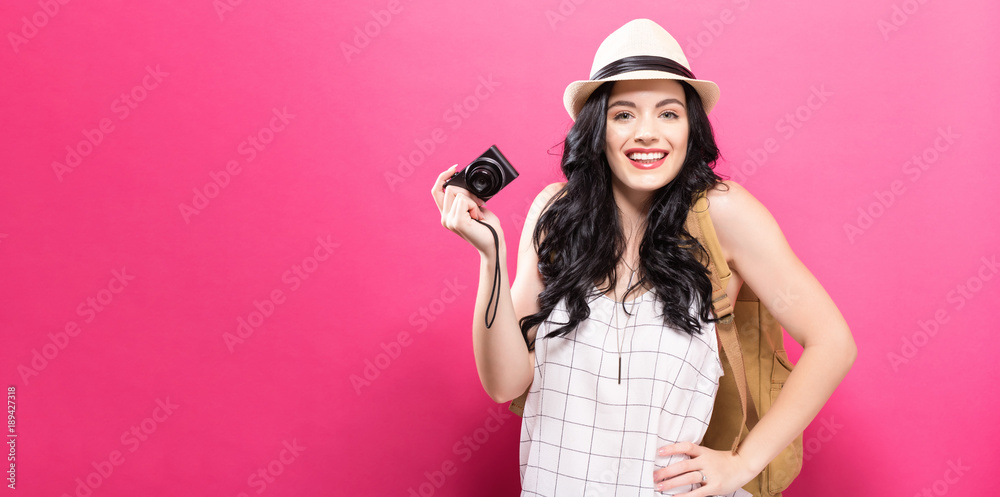Traveling young woman holding a camera on a solid background Traveling young woman holding a camera on a solid background