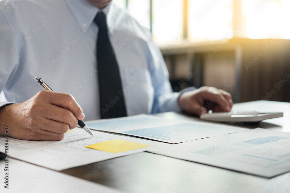 Business man working at office with laptop, tablet and graph data documents on his desk Business man working at office with laptop, tablet and graph data documents on his desk