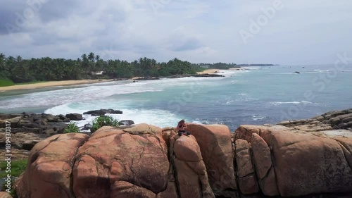 Young girl do yoga lotus namaste pose on rocky beach sunrise drone footage photo