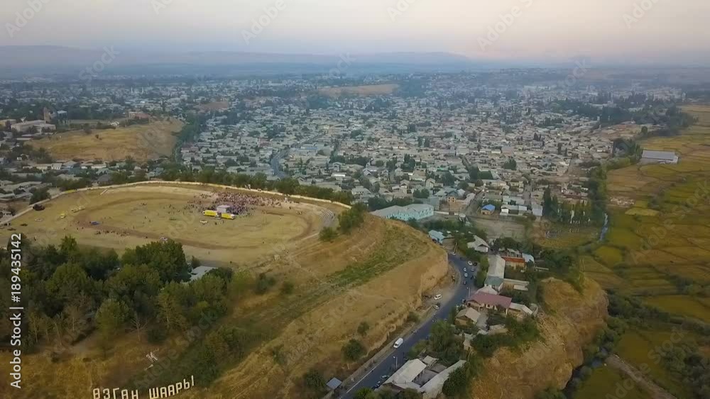 View of beautiful mountains, stadium with crowd, houses and trees with a drone on the top View of beautiful mountains, stadium with crowd, houses and trees with a drone on the top