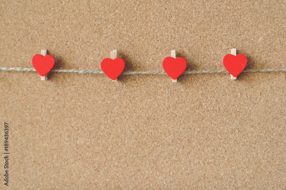 Fototapeta premium Red hearts shape pins garland over brown craft recycle cork board background. Free copy space. Valentine's day concept.