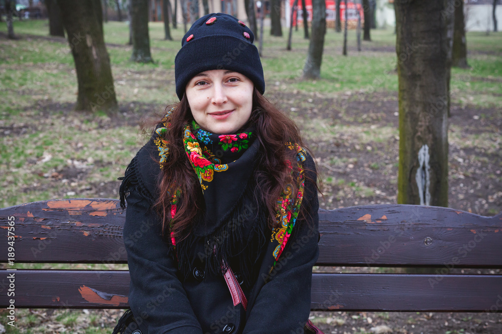 Beautiful young woman in Russian scarf sitting on bench Beautiful young woman in Russian scarf sitting on bench
