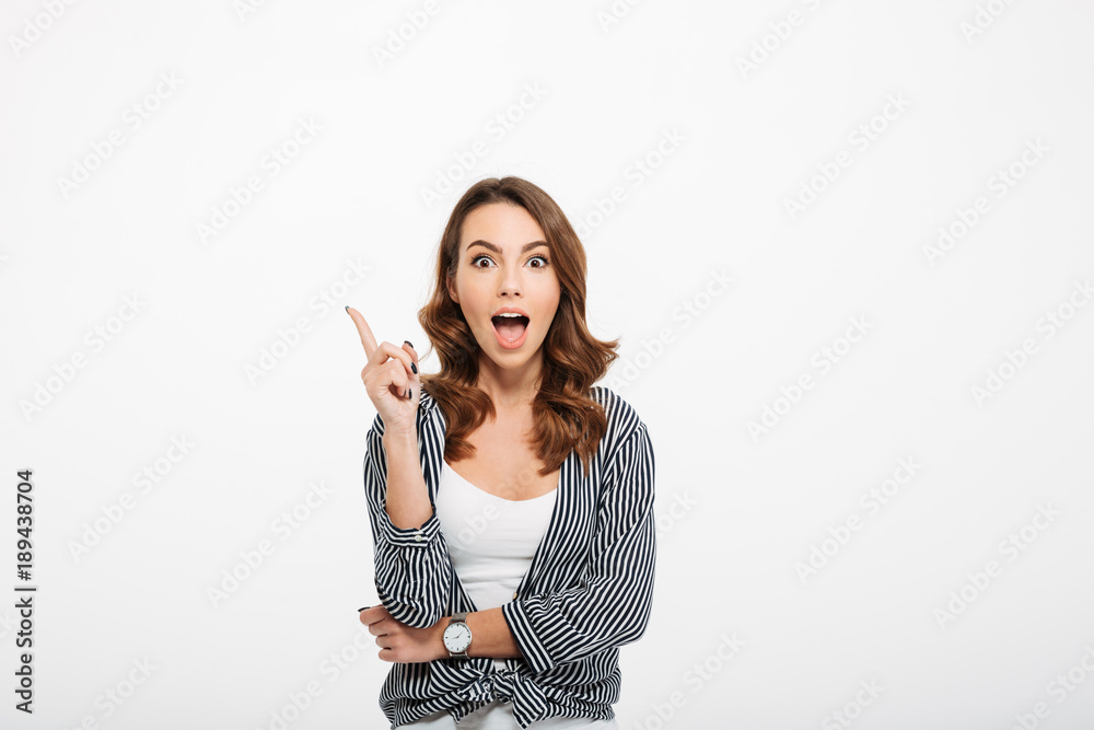 Portrait of an excited casual girl pointing finger up Portrait of an excited casual girl pointing finger up