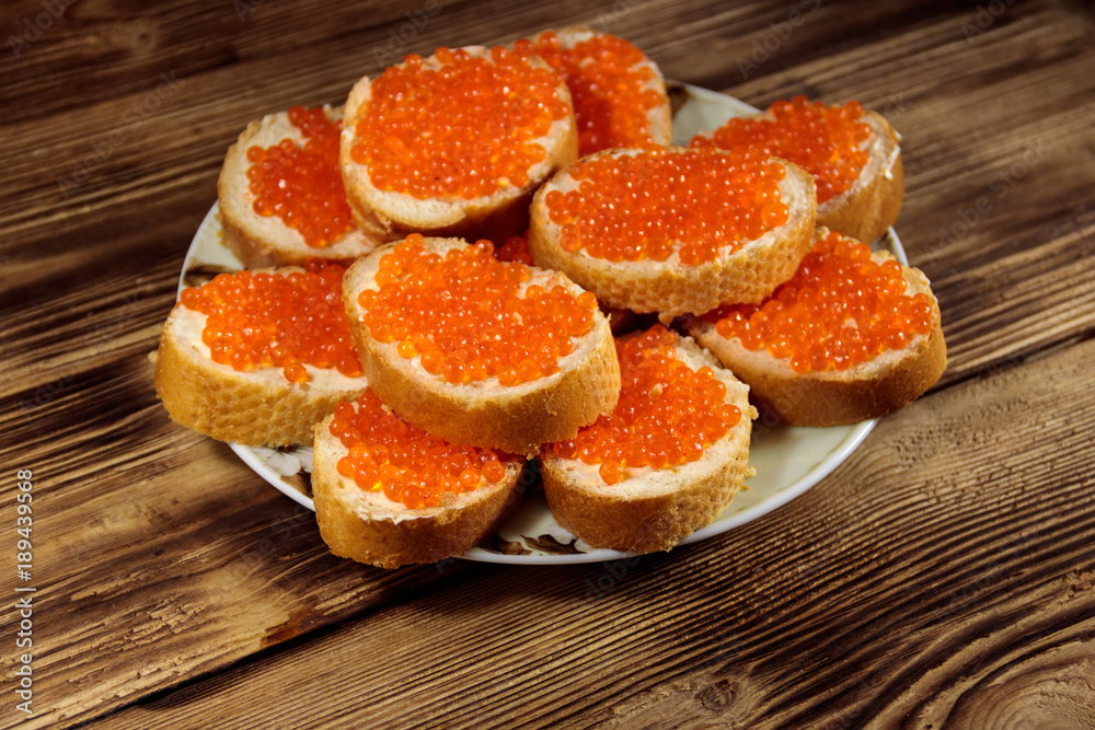 Sandwiches with butter and red caviar on wooden table Sandwiches with butter and red caviar on wooden table