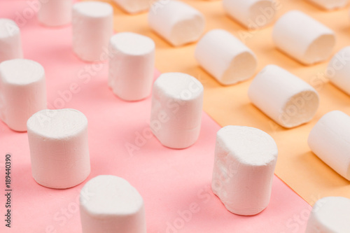 Sweet marshmallows on pastel yellow and pink background.