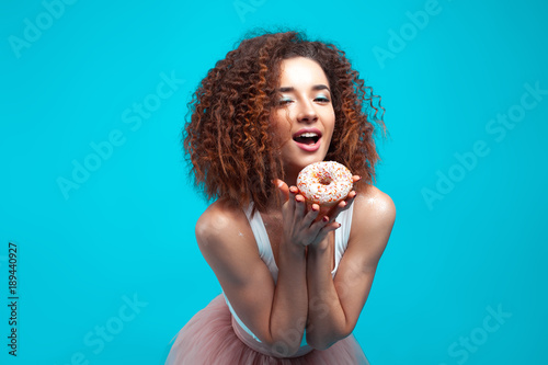 Beautiful young cheerful girl with donut in hand