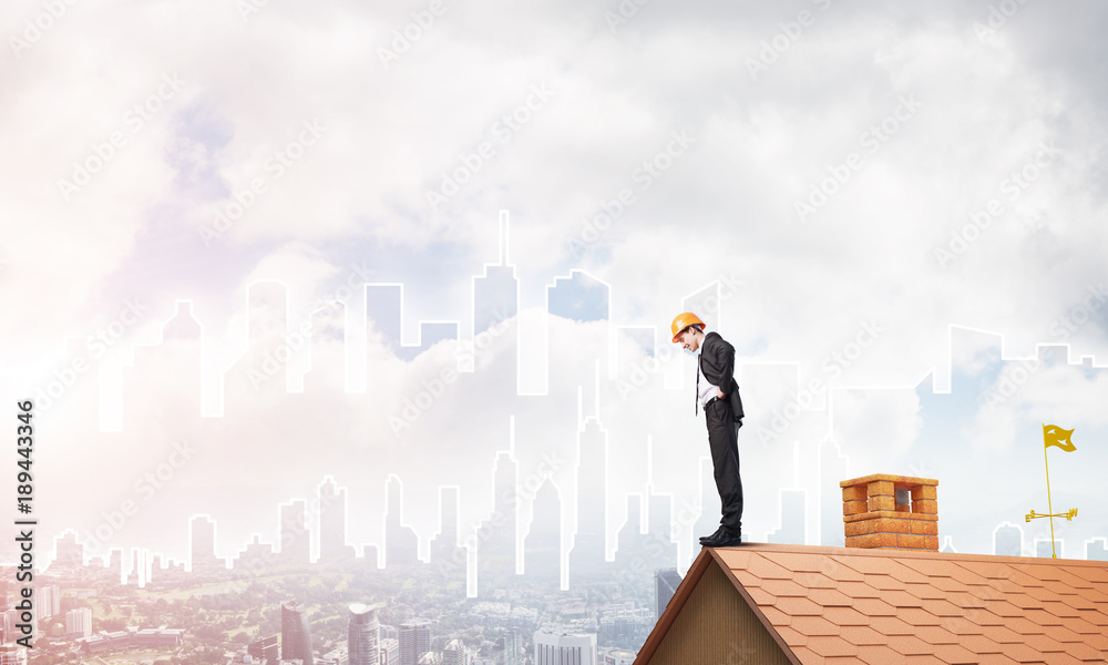 Engineer man standing on roof and looking down. Mixed media Engineer man standing on roof and looking down. Mixed media