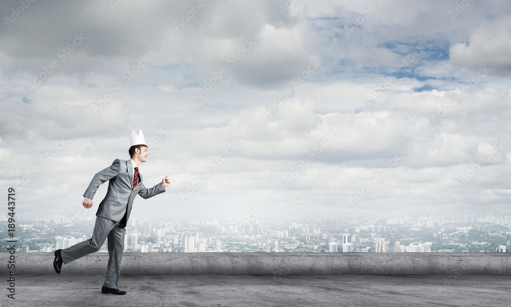 King businessman in elegant suit running on building roof and business center at background