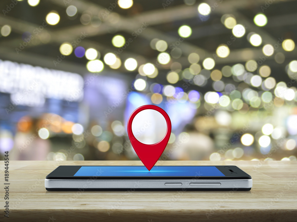 Map pin location button on modern smart phone screen on wooden table ...