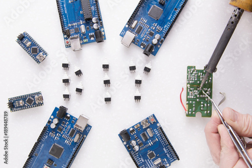 Six arduino  boards for robotics, 3D printing or developments and inventions. A man's hand with a soldering iron. You can see smoke from rosin. Learning boards in Fablab - Nano, Uno and Mega photo