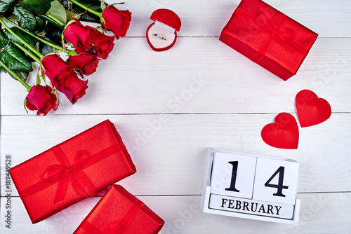 Valentines Day background with red roses, gift boxes, two hearts, diamond ring and wooden block calendar february 14, copy space. Greeting card mockup. Love concept. Top view, flat lay photo