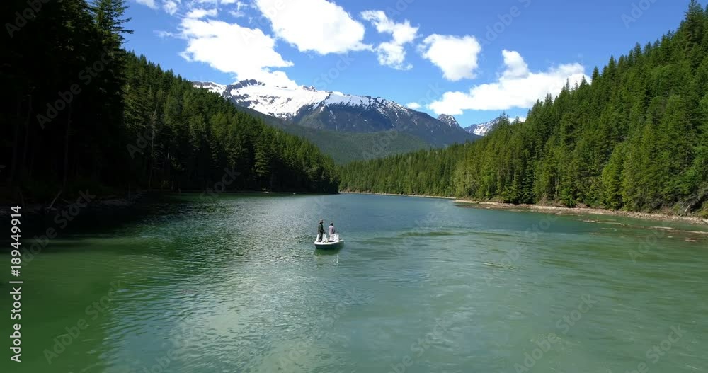 Two men fishing in the river while sailing in the boat on a sunny day Two men fishing in the river while sailing in the boat on a sunny day