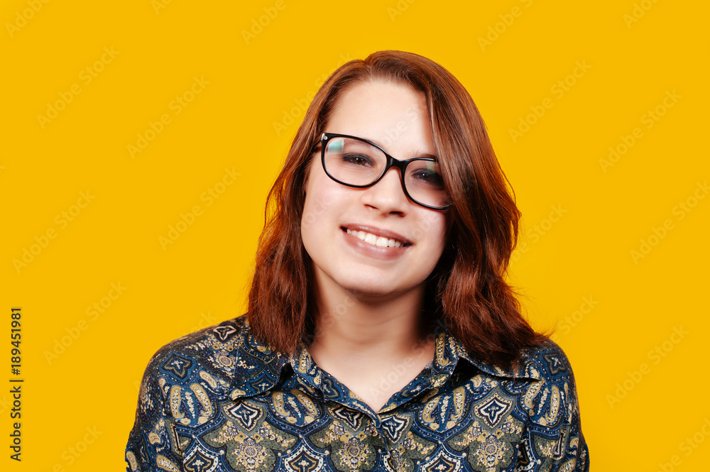 Obraz premium Cheerful young woman in eyeglasses smiling at camera on orange background.