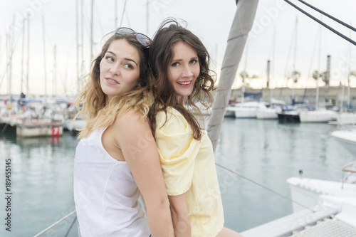 Two girlfriends relaxing on a yacht at a harbor.