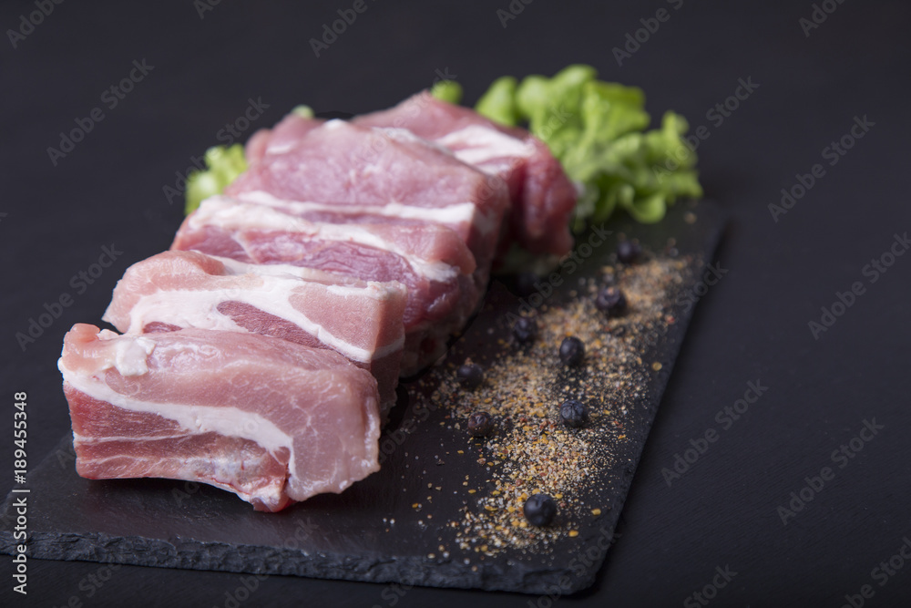 Fresh pork ribs on a dark background. Meat for cooking Fresh pork ribs on a dark background. Meat for cooking